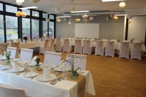 un salón de banquetes con mesas blancas y sillas blancas en Gästehaus Reckahn der Rochow Akademie, en Reckahn