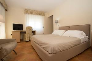 een slaapkamer met een bed, een bureau en een televisie bij Hotel Villa Serena in Castellammare di Stabia