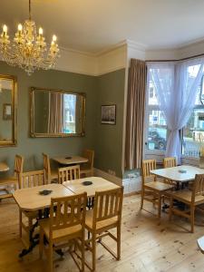 uma sala de jantar com mesas e cadeiras e um lustre em Waverley Park Lodge em Portsmouth