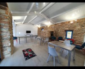 Cette chambre est dotée de tables, de chaises et d'un mur en briques. dans l'établissement A Casa do Lado, à Melide