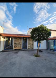 a house with a tree in a parking lot at A Casa do Lado in Melide