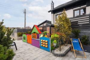 un jardín con un parque infantil de juguetes frente a una casa en Ambre Apartments, en Łeba