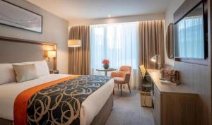 um quarto de hotel com uma cama, uma secretária e uma televisão em Clayton Hotel Manchester City Centre em Manchester