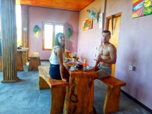 Ein Mann und eine Frau sitzen an einem Tisch in einem Zimmer. in der Unterkunft Gentari Homestay and Tour in Nusa Penida
