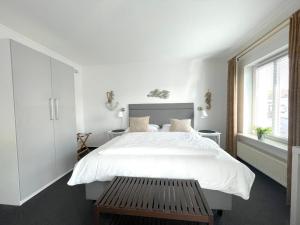 Westerstrasse 6 في بوسوم: غرفة نوم بيضاء بسرير كبير ومقعد