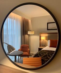 una camera d'albergo con letto e specchio rotondo di Clayton Hotel Manchester City Centre a Manchester