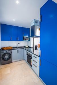 a blue kitchen with blue cabinets and a dishwasher at Casa Maravilha III in Caniço