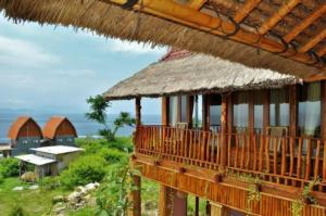 ein Gebäude mit einem Strohdach und einem Balkon in der Unterkunft Gentari Homestay and Tour in Nusa Penida