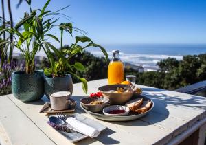 a table with plates of food and a bottle of orange juice at Wilderness Beach House Backpackers Lodge in Wilderness