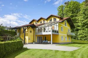a yellow house with a porch and a lawn at Seeblick Susanne in Schiefling am See