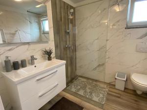 a bathroom with a sink and a shower and a toilet at Apartman Veronika in Risika +9 photos