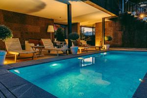 a swimming pool with chairs and a patio at Casa das Mourôas in Mondim de Basto