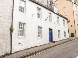 a white building with a blue door on a street at Springwells in Dunkeld