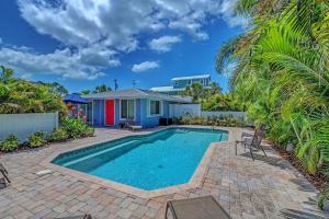 a swimming pool in front of a house with palm trees at Salt Air East by Beach Retreats in Holmes Beach