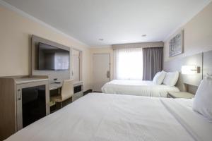 Habitación de hotel con 2 camas, escritorio y TV. en Hotel Aspen Flagstaff/ Grand Canyon InnSuites en Flagstaff