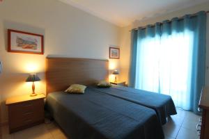 ポルティマンにあるApartamentoSolPraia - FAIAのベッドルーム1室(ベッド1台、青いカーテン付きの窓付)