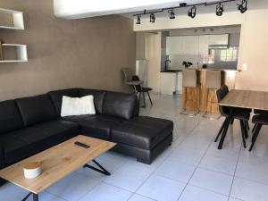ein Wohnzimmer mit einem schwarzen Sofa und einem Tisch in der Unterkunft Bâtisse du pont Pinard et son granit rose in Semur-en-Auxois