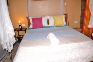 um quarto com uma cama grande e almofadas coloridas em Mondi Lodge Kisoro em Kisoro