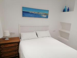 een slaapkamer met een wit bed en een houten dressoir bij Old Side Duplex Platja d'Aro in Platja  d'Aro