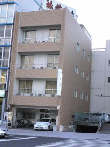 un edificio alto de ladrillo con coches estacionados frente a él en Tenryu Ryokan, en Hiroshima