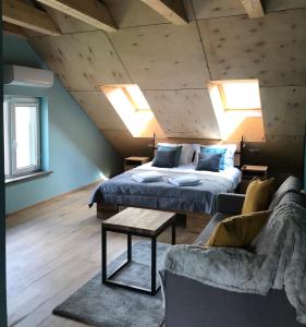 a bedroom with a bed and a couch and skylights at Daukanto apartamentai in Anykščiai