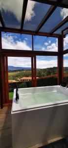 a bath tub in a room with a large window at Villa Monica HR in Villa de Leyva