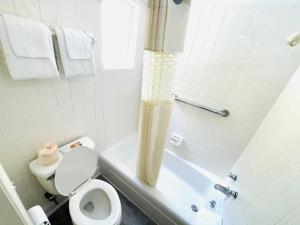 a white bathroom with a toilet and a bath tub at Relax Inn - Perry in Perry