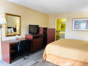 a hotel room with a bed and a desk and a television at Relax Inn - Perry in Perry