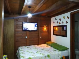 a bedroom with a bed and a tv in a room at Chalés Praia do Rosa piscina compartilhada in Imbituba