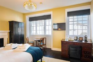 a bedroom with a bed and a desk and two windows at Lyme 1 Hotel in Lyme Regis