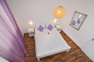 Cette chambre comprend un lit blanc avec des oreillers violets. dans l'établissement Apartmani i sobe Josica, à Jezera