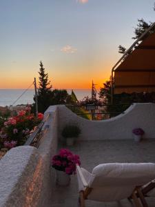 einen Sonnenuntergang auf einer Terrasse mit Stühlen und Blumen in der Unterkunft Vista Stromboli in Paola