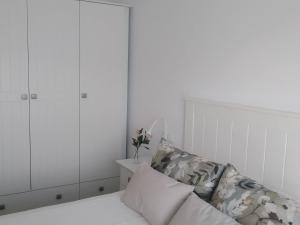 biała sypialnia z łóżkiem i białymi szafkami w obiekcie La Tinajita w mieście Sanlúcar de Guadiana
