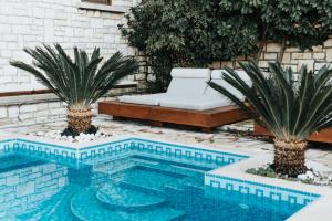 a swimming pool with two palm trees and a bench at Villa Milena in Syvota