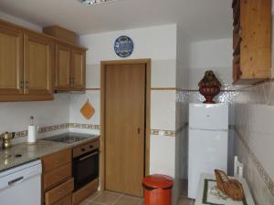 a kitchen with a white refrigerator and wooden cabinets at Casa do Castelo in Redondo
