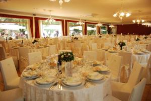 une salle de banquet avec des tables blanches et des chaises blanches dans l'établissement Hotel Villa Pigna, à Ascoli Piceno