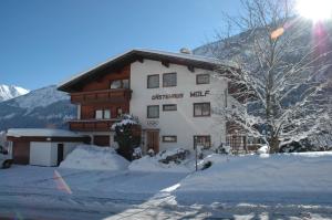 a building in the snow in front of a mountain at Gästehaus Wolf in Elbigenalp