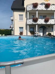 a man in a swimming pool in front of a building at Pensjonat Amor in Mielno