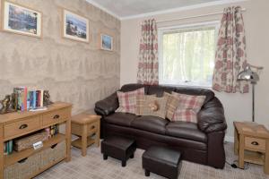 sala de estar con sofá de cuero y ventana en The Bridge Suite, en Invermoriston