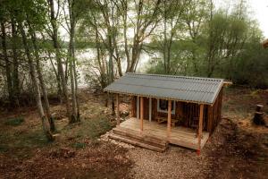 uma pequena cabana na floresta com um telhado de estanho em Rijnieki upes namiņš em Koknese