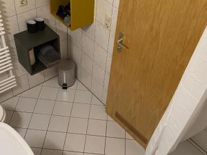 a bathroom with a toilet and a wooden door at Ferienwohnung am Stötteritzer Wäldchen in Leipzig