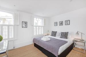 um quarto branco com uma cama e 2 janelas em Lovely 1-Bed Apartment in London em Londres