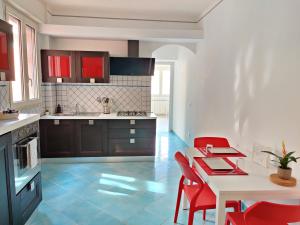 a kitchen with a white table and red chairs at Casa Atena in Sperlonga
