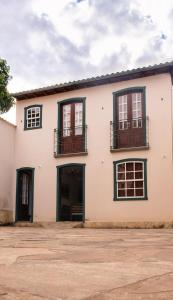 a white building with black windows and balconies at Solar de Amelia in Tiradentes