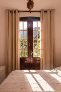 a bedroom with a bed and a large window at Solar de Amelia in Tiradentes