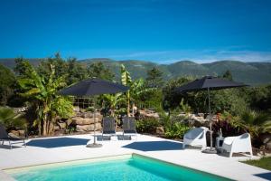 a swimming pool with chairs and umbrellas and mountains at Casa Gemeos in Alcobaça