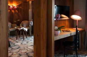 a room with a desk with a television and a chair at Alexander Charme Hotel in Livigno