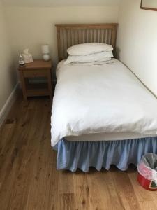 a bedroom with a bed and a wooden floor at Lane End Cottage in Ovington