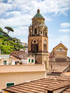 un antiguo edificio con una torre de reloj en una ciudad en Hotel Amalfi, en Amalfi