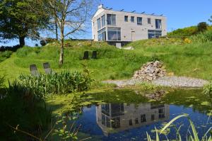 a house sitting on top of a hill next to a pond at La Lisière in Durbuy
